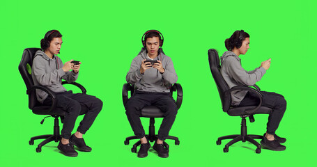 Asian person playing mobile games over full body greenscreen, holding smartphone to play online rpg contest. Modern gamer using phone gadget to have fun with new gameplay on chair.
