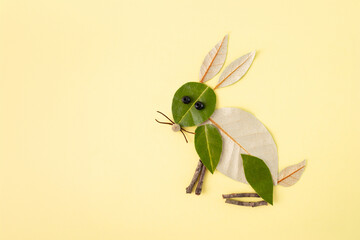 Creative hare made from leaves and natural materials on plain yellow background