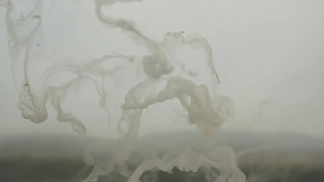 Wispy tendrils of fog swirl above a landscape during a misty morning in a serene environment