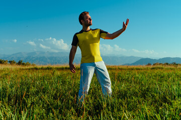 Fototapeta premium Young strong successful man posing in summer meadow on mountains background