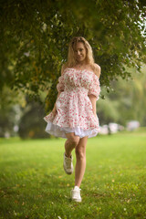 A Beautiful and Elegant Young Woman in a Lovely Summer Dress Posing Gracefully Outdoors