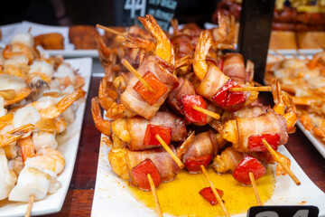 Typical snacks of Basque Country, pinchos or pinxtos skewers with small pieces of bread, fish, sea food, sweet green pepper served in bar in San-Sebastian or Bilbao, Spain