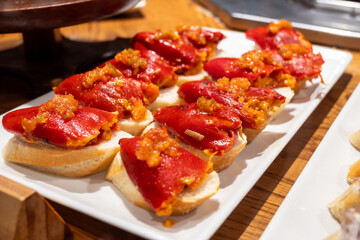 Typical snacks of Basque Country, pinchos or pinxtos skewers with small pieces of bread, fish, sea food, sweet green pepper served in bar in San-Sebastian or Bilbao, Spain