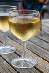 Tasting of Bordeaux white wine in Sauternes, left bank of Gironde Estuary, France. Glasses of white sweet French wine served in outdoor restaurant