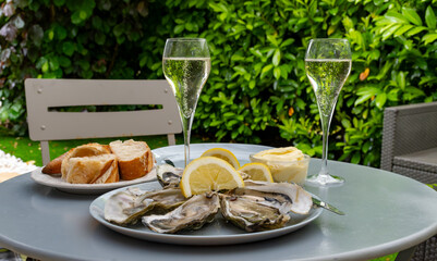 Champagne sparkling wine in glasses and oysters from Arcachon bay served on oysters farm in Gujan-Mestras, with lemon, baquette bread, butter