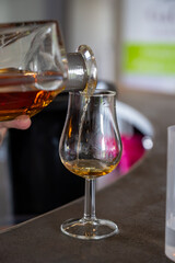 Enologist tastis and sniffs cognac spirit aged in old dark French oak barrels in cellar distillery house, Cognac white wine region, Charente, Segonzac, Grand Champagne, France