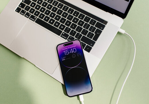 Paris, France - Sep 29, 2022: A USB-C cable charging the latest iPhone 15 Pro smartphone connected to a laptop, showcasing the modern compatibility and fast charging feature between devices