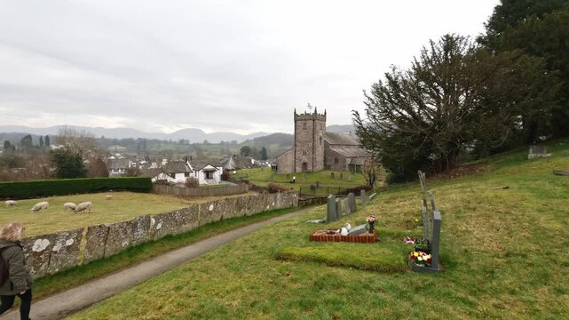 St Michael & All Angels Church in Hawkshead, showing fields and grazing sheep Cumbria,