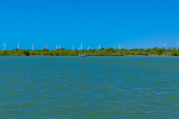 VIEW OF THE JAGUARIBE RIVER IN THE MUNICIPALITY OF FORTIM ON THE EAST COAST OF THE STATE OF CEARÁ WITH A RENEWABLE ENERGY WIND FARM UNDER THE SAND DUNES IN THE BACKGROUND.