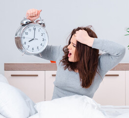 Young woman lying on the bed in time management concept