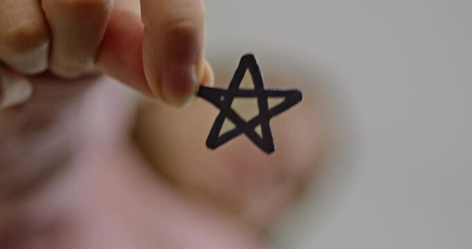 A close-up of a woman's hand holding a star-shaped cutout with a blurred background, highlighting simplicity and creativity.