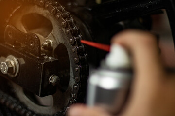 Close-up of a bicycle mechanic cleaning a chain with chain lube spray