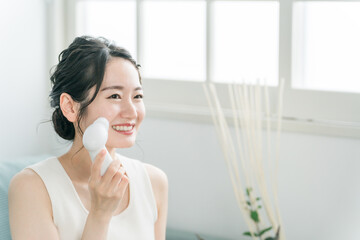 洗顔器・洗顔ブラシを使って洗顔する若いアジア人女性
