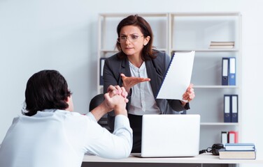 Old female boss and young male employee in the office
