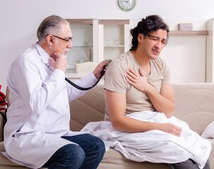 Obraz premium Old male doctor visiting young male patient