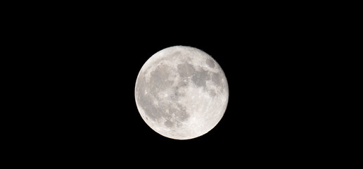 A photo of a white full moon. A harvest moon in the autumn night sky.