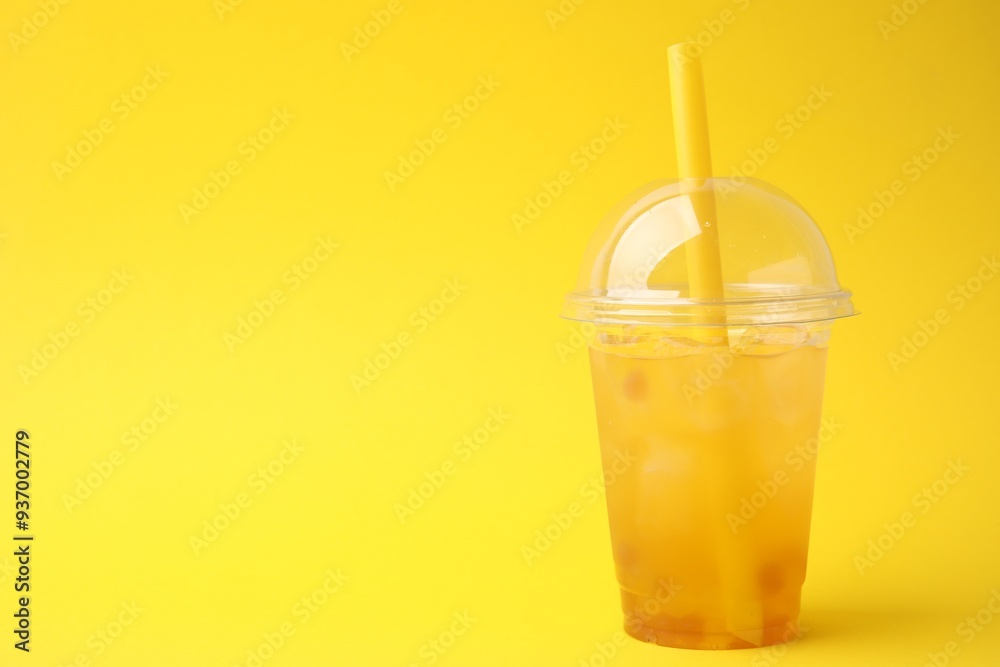 Poster tasty bubble tea in plastic cup on yellow background, space for text