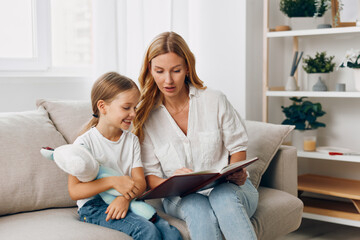 Mother and daughter bonding on a cozy couch, sharing a storybook and cuddling a stuffed animal