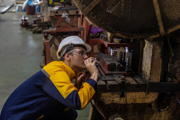 Male mechanical or metallic engineer is using a torch light to check a welding machine for...