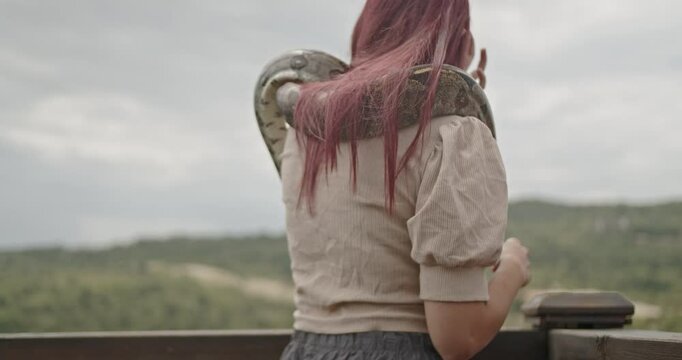 A happy young adult woman enjoys time outdoors with her pet snake.