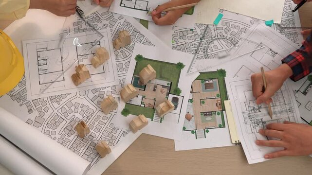 Architect and safety engineer discussion about building construction use blueprint on table with architectural document, measurement tool and wooden block scatter around at modern office. Delineation.