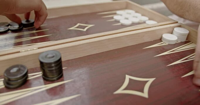 Close-up of hands moving checkers on a backgammon board. The image captures the excitement and strategy of the game.