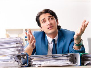 Young handsome busy employee sitting in office