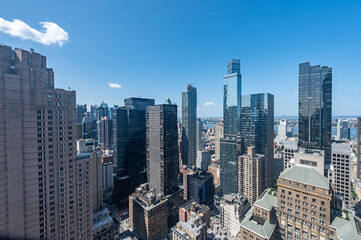 Fototapeta premium These stunning images capture the iconic New York City skyline from a high vantage point, showcasing the impressive architecture and towering skyscrapers that define the city. The clear blue sky provi
