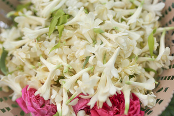 Polianthes tuberosa, and some pink rose cuttings in a bowl for a wedding event with a green grass background