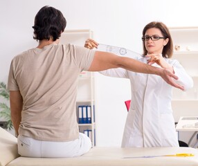 Fototapeta premium Female doctor checking patient's joint flexibility with goniomet