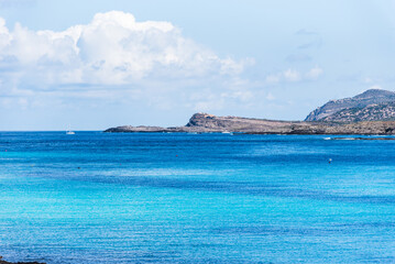 Naklejka premium A tranquil blue bay stretches towards the horizon, where Isola Piana rises gently from the sea. Set opposite the famed La Pelosa beach.