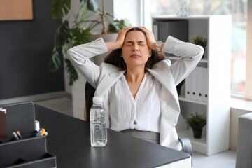 Young woman suffering from headache sitting in office