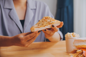 Cropped image of woman holding pizza slice at restaurant