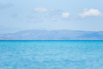 Le Saline beach landscape: turquoise sea meets a distant horizon with faint landforms, under a vast...