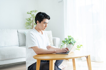 自宅でパソコン作業をする爽やかな男性