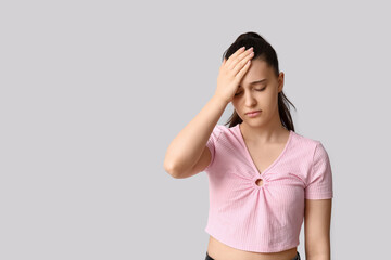 Beautiful young woman suffering from headache on white background