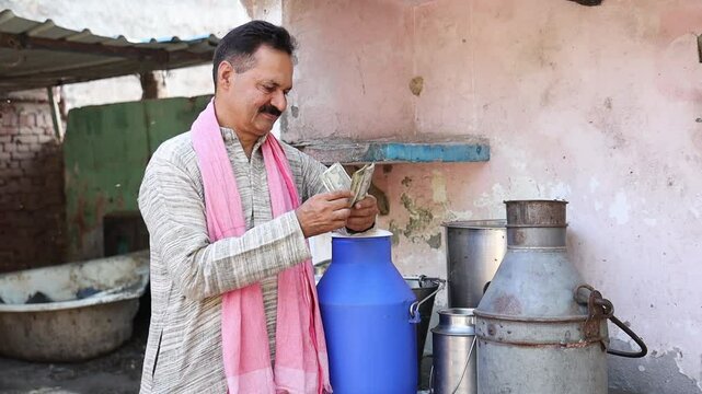 Happy rural Indian dairy farmer counting money after selling milk, representing profitable farming business, income growth, and financial success in agriculture industry