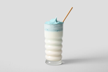 Glass of blue dalgona matcha latte with straw on white background