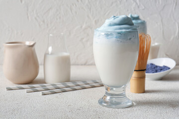 Glass of blue dalgona matcha latte and chasen on grunge table, closeup