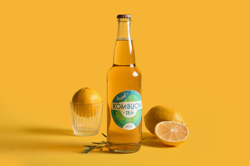 Bottle of tasty kombucha tea with lemon and rosemary on yellow background