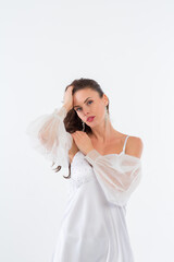 A young girl in a beautiful white dress in a white photo studio.