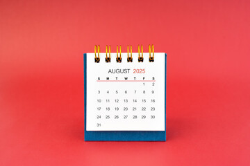 August 2025 white desk calendar on red background.