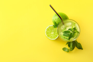 Glass of fresh lemonade with lime and mint on yellow background