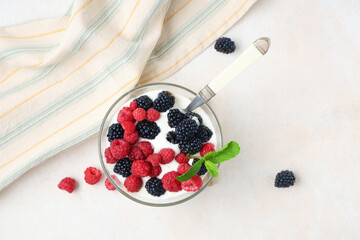 Glass bowl of tasty yogurt with fresh blackberries and raspberries on white background
