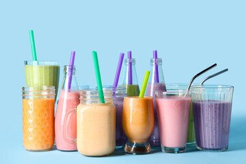 Glasses and bottles of different fresh smoothie on blue background