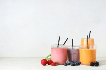 Glasses of fresh smoothie with different berries on white background