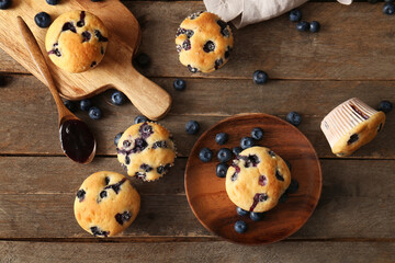 Wooden tray, plate and tasty blueberry muffins on wooden background