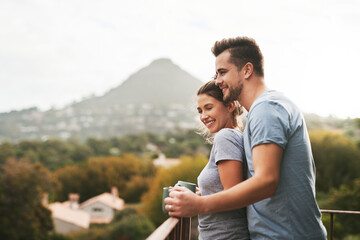 Happy, couple and hug with coffee on balcony for morning espresso, romance breakfast or mountain view in London. Smile, man and woman with warm drink, marriage honeymoon and embrace for love at house