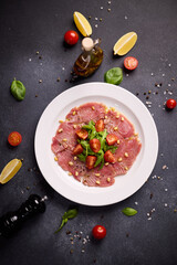 cooking tuna carpaccio - Fresh raw tuna fillet with olive oil and pine nuts on white ceramic plate