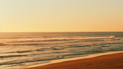 Obraz premium Ocean Waves Crashing on a Sandy Beach at Sunset